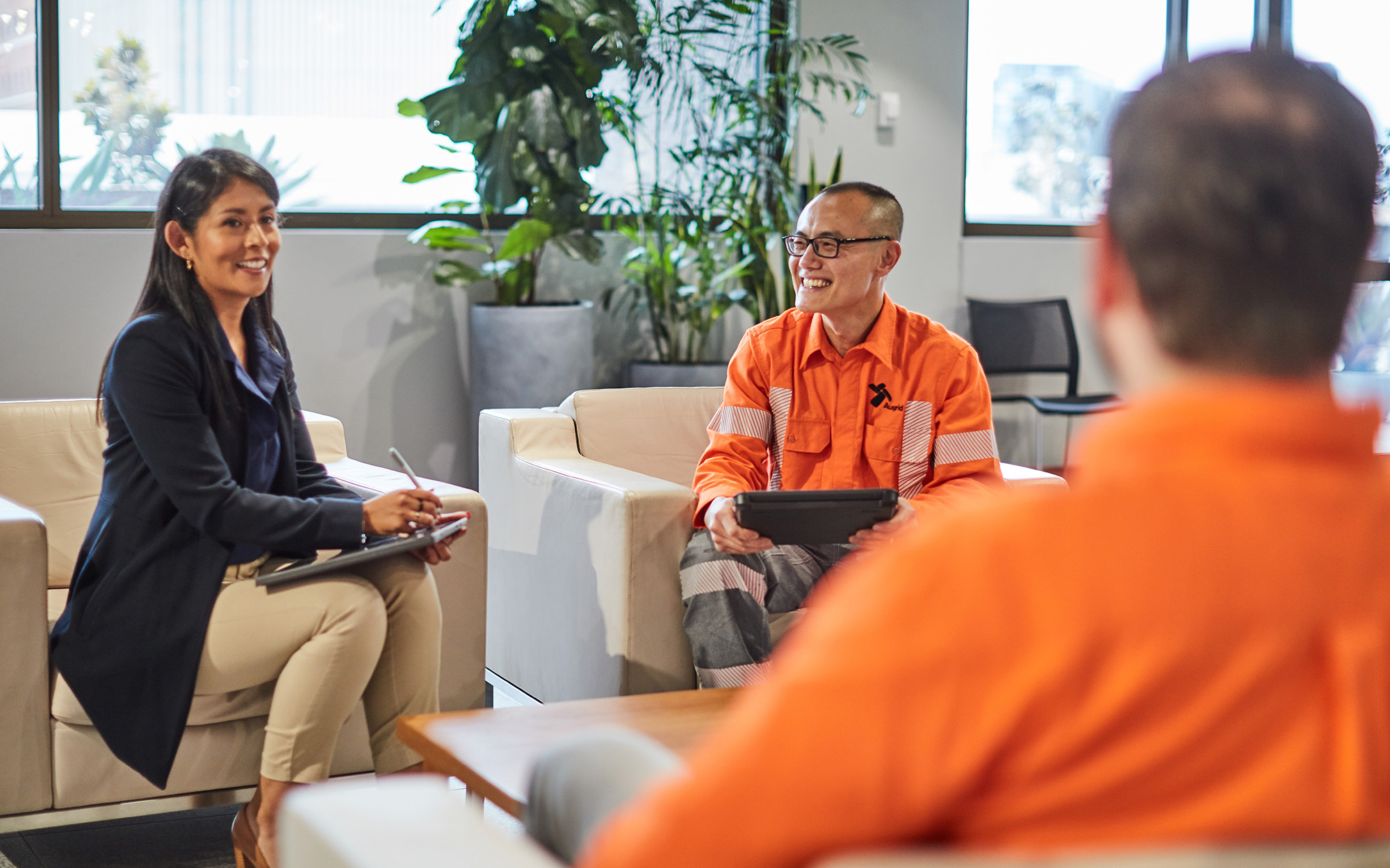 Members of Ausgrid's Employee Groups sitting chatting, lady in blazer and field workers sitting in chairs.
