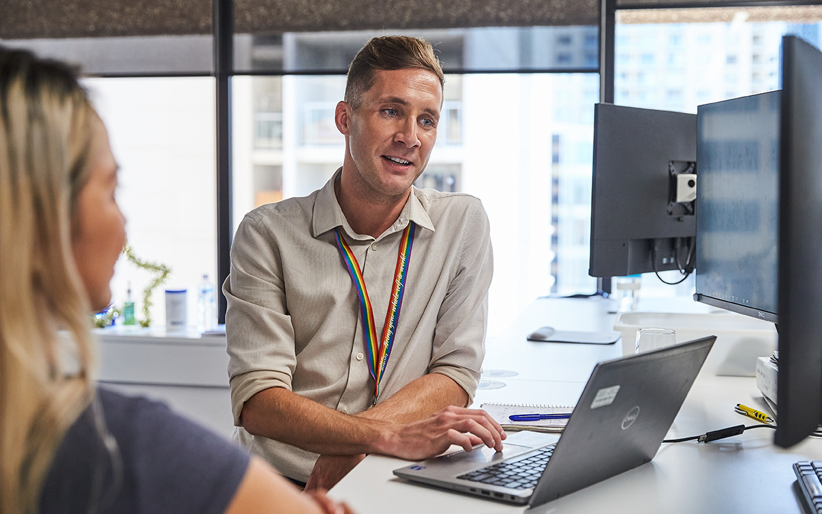 Two employees (male and female) discussing something in front of a latop