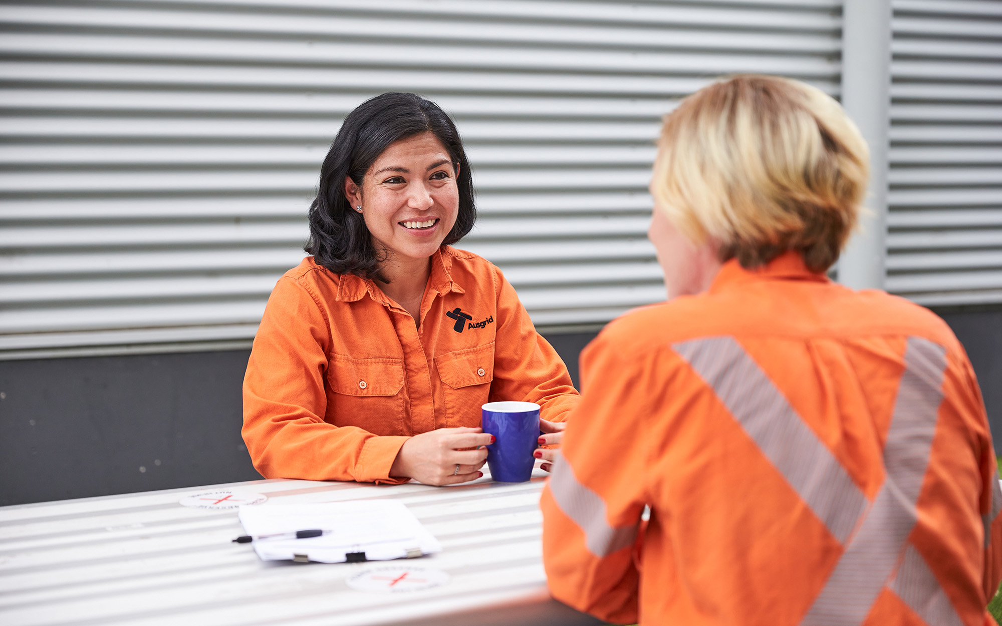 Two female employees in a meeting room chatting