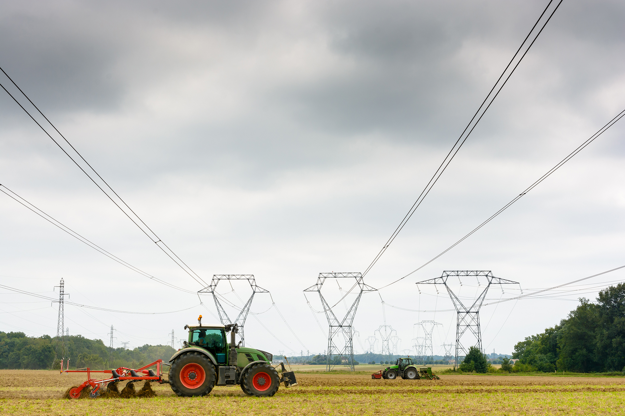 Tractors underneath powerlines on farm.